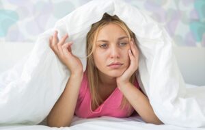 Сънливостта през деня. Следродилна депресия. Ушна инфекция. Стресирана и уморена жена. Млада жена не може да заспи в леглото.