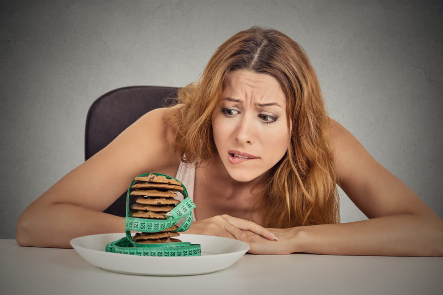 жена, която се притеснява за килограмите си, гледаща в сладки, скритата захар в храните