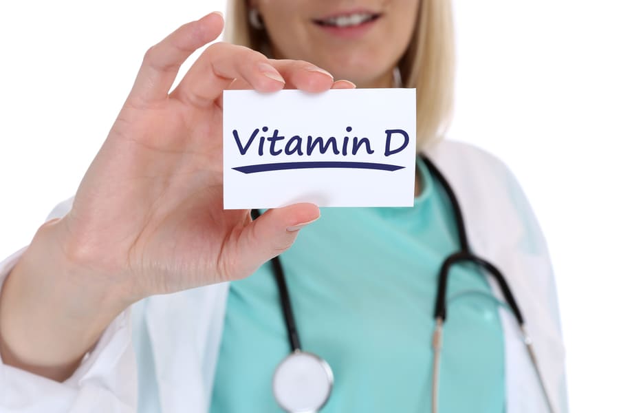 Факти за витамин Д. Свинска мас за готвене. Лекарка, която държи табелка с надпис витамин D