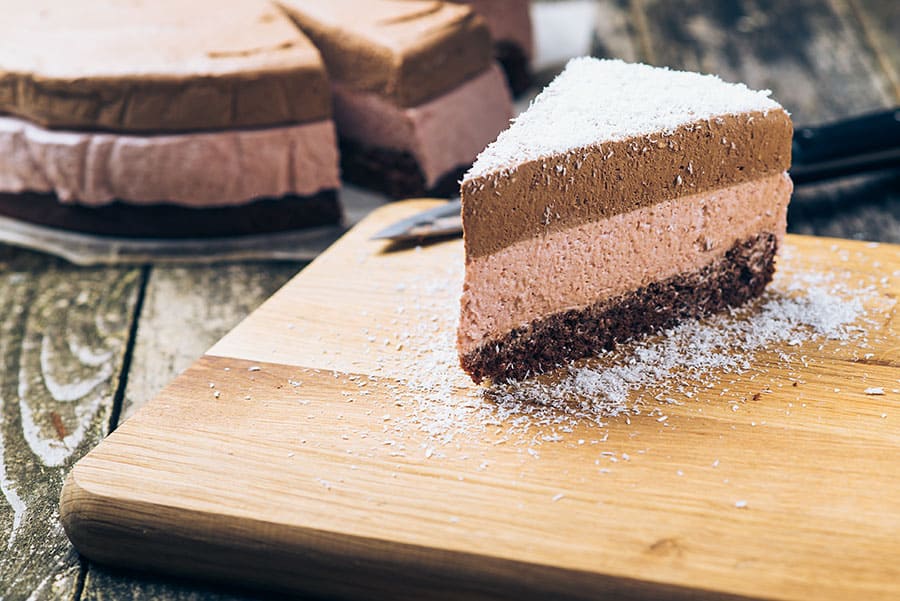 Как да се храним през лятото. кокосово брауни в триъгълна форма, отделно парче на фон на цяла торта