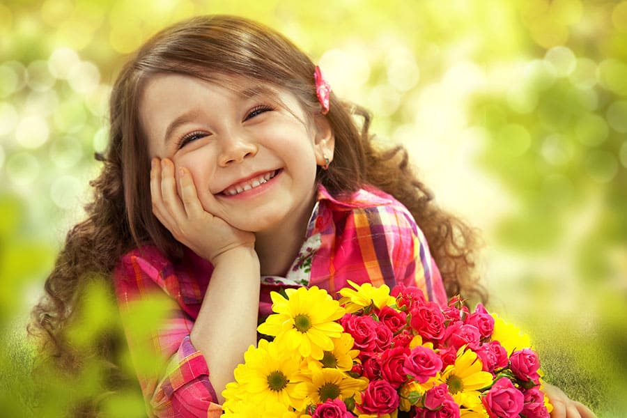 Цветница. Весело и усмихнато лице, легнало на една поляна и гушнало букет с цветя.
