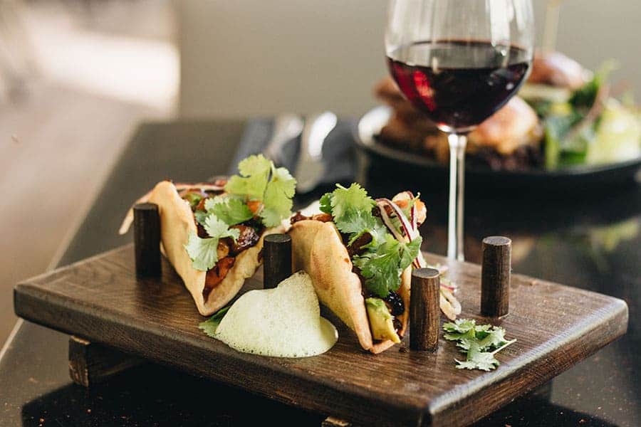 чаша червено вино със здравословни сандвичи, опднесени на стара дървена табла с място за поставки.