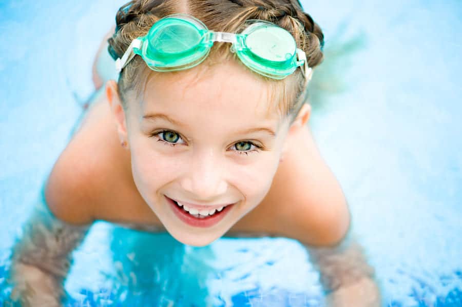 Таласотерапия, море. Бенки. Малко русо момиченце, сплетено на плитки, с плувни очила, заснето в басейн.