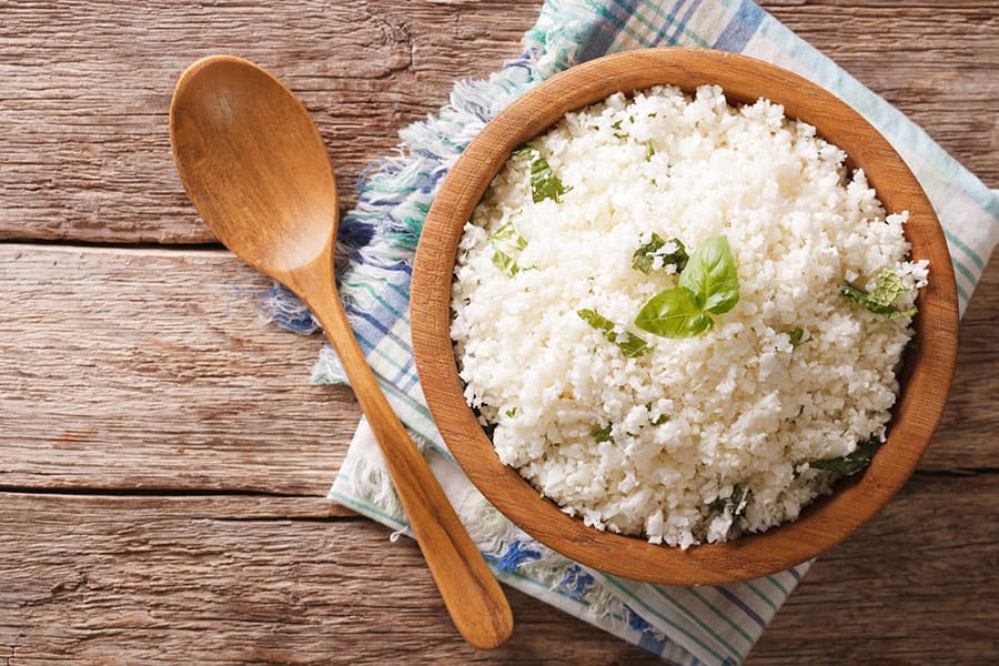 Здравословен ориз от карфиол, поставен в купа на масата.