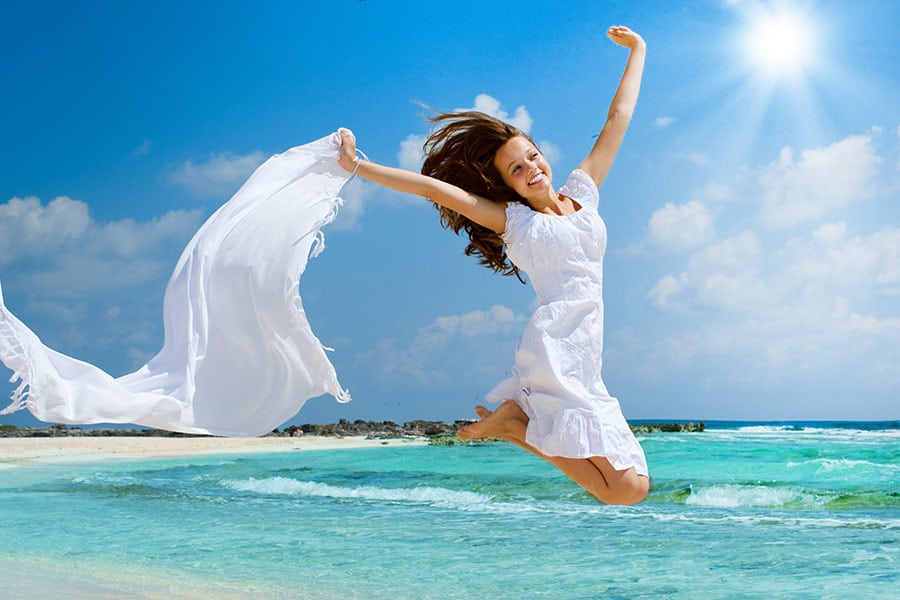 Билки при паник атаки. Таласотерапия, море. Цветотерапията. Здрава и щастлива млада жена скача във въздуха на плажа. Пробиотик съдейства за доброто женско здраве през лятото.