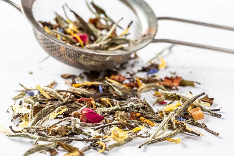 White tea with flowers, petals and rosebuds on white background. Close up of chinese white tea of premium luxury quality. Texture background macro photo. Bai Hao Yinzhen tea.