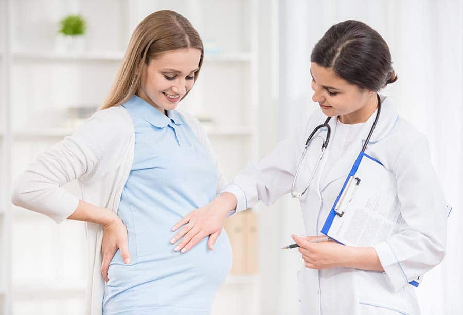 Жена по време на бременност на посещение при лекар, мерки по време на коронавирус. Тревожност по време на бременност.