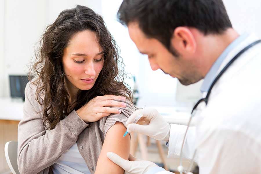 Лекар поставя ваксина на млада жена срещу грипните вируси.