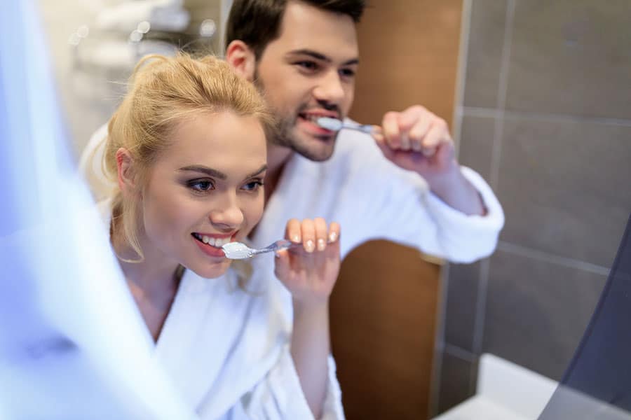 Мъж и жена, които си мият зъбите и пестят водата, като ресурс.