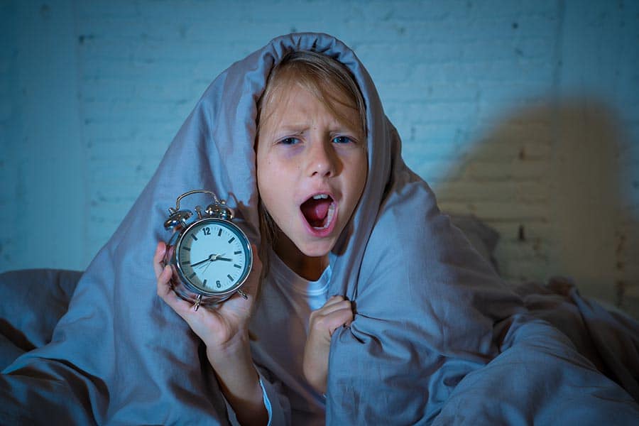 Непрекъснат глад при кето диета. Снимка на дете, държащо часовник, събудено късно през нощта заради проблеми с безсънието.