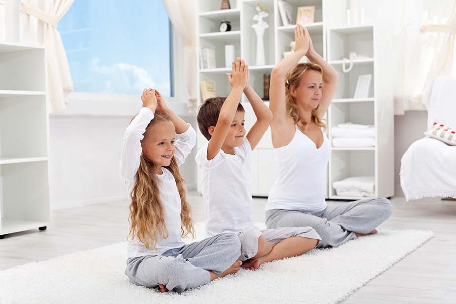 Балансираният начин на живот, майка прави йога с децата си.